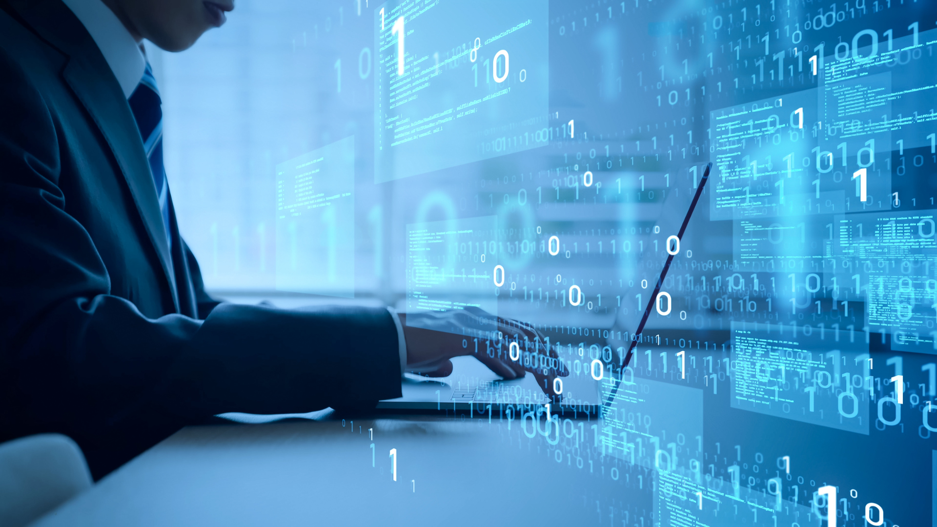 Persona con traje escribiendo en una computadora portátil, rodeada de códigos binarios y pantallas flotantes de programación en un entorno digital.