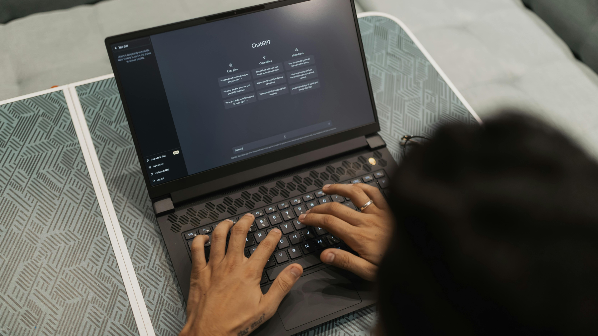 Vista superior de una persona escribiendo en una computadora portátil con la pantalla mostrando la interfaz de inicio de ChatGPT.