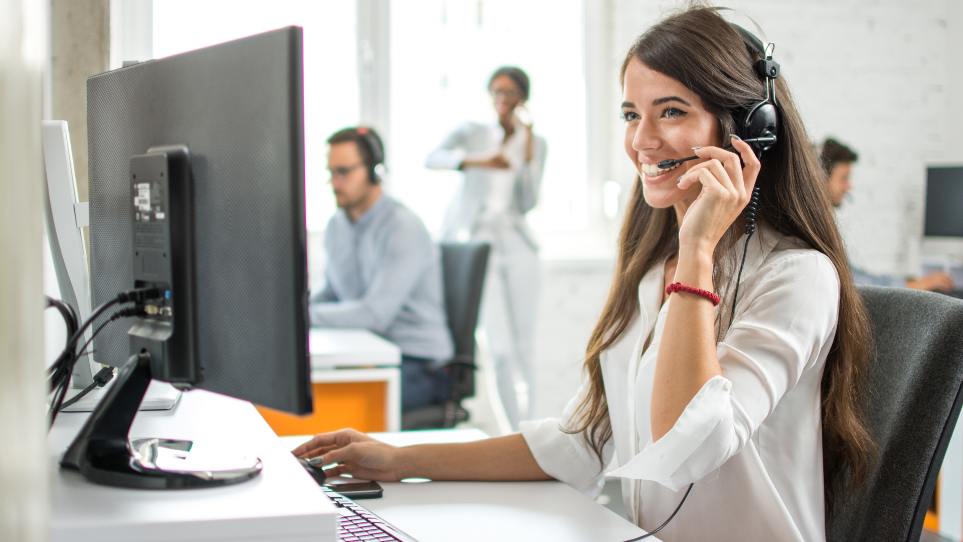Operadora de atención al cliente con auriculares trabajando en oficina